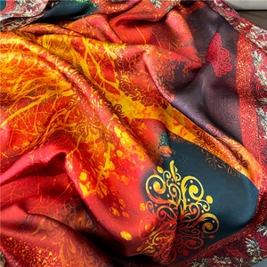 Close-up of luxury floral silk scarf showing vibrant red and orange satin texture