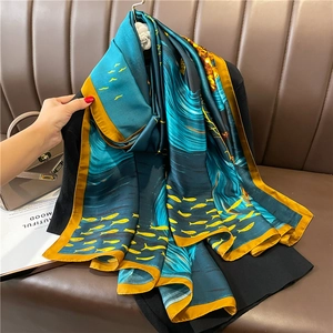 Detail of luxury silk scarf with yellow fish print and bright yellow borders on blue fabric