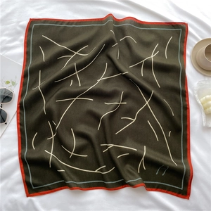 Vista dall'alto di un foulard quadrato verde oliva con bordo arancione e linee bianche