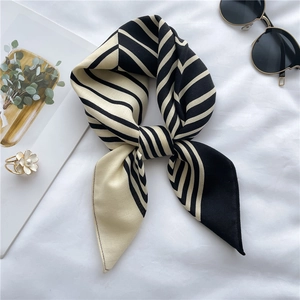 Detail of elegant black and beige striped silk scarf tied in a bow with stylish accessories