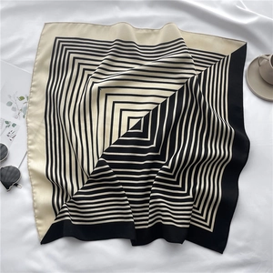 Detail view of a black and white geometric stripe silk scarf on a lifestyle background