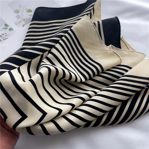 Close-up of striped silk-like scarf with black and cream patterns on a soft background