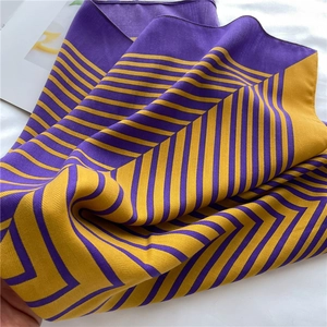 Detailed view of striped silk-like scarf with glossy purple and mustard yellow texture