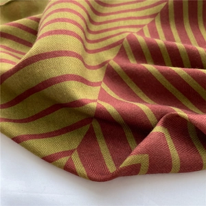 Detailed view of red and green herringbone weave texture on a soft striped scarf