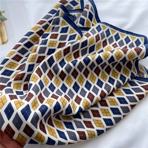 Détail d'un foulard en soie à losanges montrant la texture sergée bleu marine et moutarde