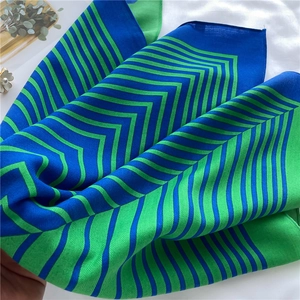 Detailed close-up of emerald green and royal blue silk scarf with classic zigzag patterns