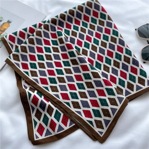Détail d'un foulard en soie à losanges avec couleurs rétro et bordures cousues