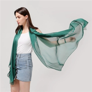 Dettaglio della sciarpa in chiffon verde scuro che mostra la texture leggera e fluida