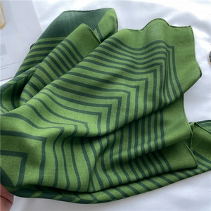 Detailed view of the dark green chevron pattern and silk-like texture of the square scarf