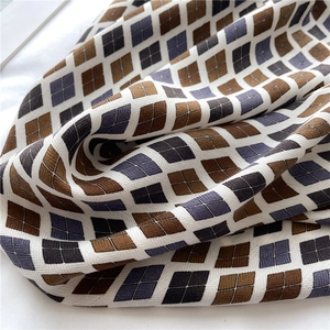Détail d'une écharpe tricotée à motifs géométriques losanges tricolores et texture dense