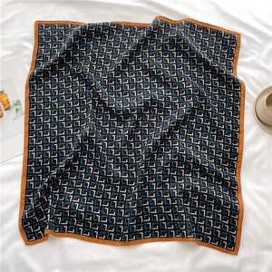 Detailed view of geometric pattern silk scarf with contrast borders in lifestyle setting