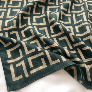 Close-up of herringbone texture on dark green silk scarf with beige geometric pattern