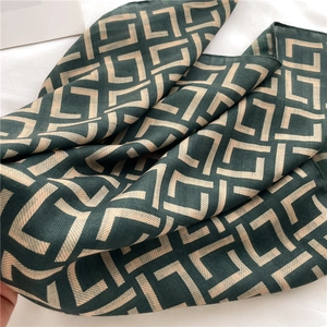 Close-up of geometric jacquard pattern and herringbone texture on green and beige scarf