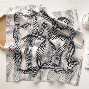 Détail d'un foulard en soie léger aux motifs géométriques noir et blanc sur plateau bois