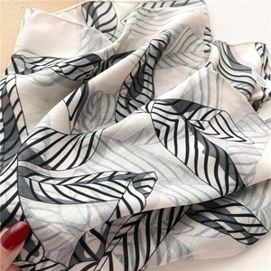 Détail d'un foulard élégant à imprimé feuilles, texture douce et bords roulés fins