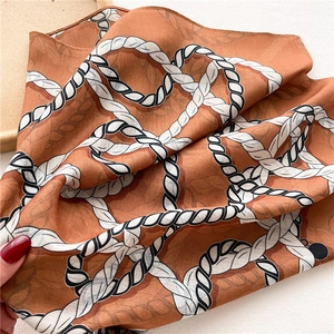 Détail de la texture d'un foulard en soie caramel avec motif imprimé de cordes bicolores