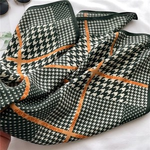 Détail d'un foulard en soie pied-de-poule vert avec rayures orange et bordure fine