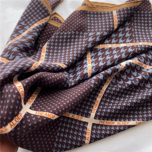 Gros plan d'un foulard en soie à motif pied-de-poule montrant la texture du tissu