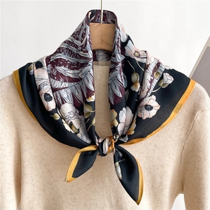 Floral silk square scarf with vintage pattern tied over a beige knit sweater