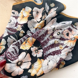 Detailed view of floral silk scarf featuring yellow hand-rolled edges and poppy prints