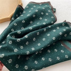 Macro detail of dark green herringbone scarf featuring leaf patterns and fine stitching