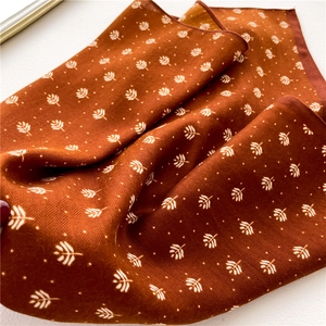 Close-up of brown scarf with white leaf pattern and herringbone texture fabric