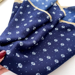 Close-up of dark blue silk scarf with white leaf patterns and twill weave texture
