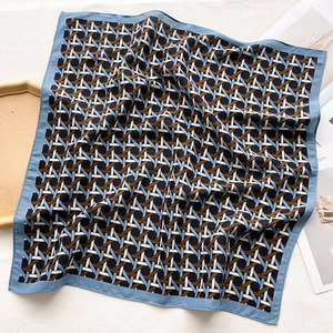 Detail of geometric woven pattern square scarf with blue border on white fabric