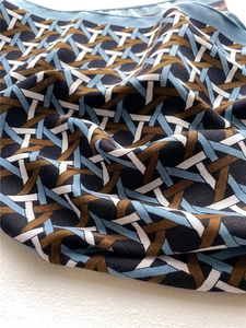 Detailed close-up of geometric lattice pattern and twill texture on soft silk-velvet scarf