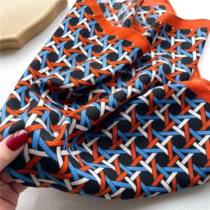 Close-up of geometric woven pattern scarf in bright orange and sky blue silky fabric