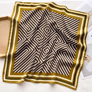 Detail of geometric stripe silk scarf with maze patterns in mustard yellow and brown