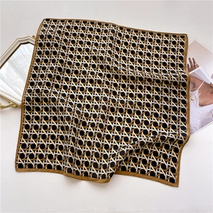 Detailed view of geometric weave pattern on silk-feel square scarf with gold trim