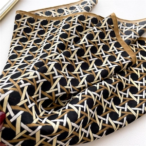 Detailed close-up of geometric woven pattern silk scarf in black, white, and gold brown