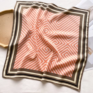 Detail of square silk scarf with orange geometric patterns and delicate soft folds