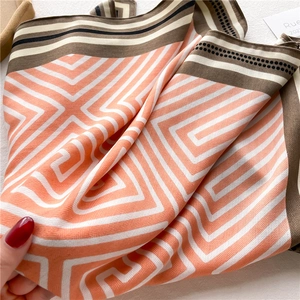 Close-up of geometric striped silk scarf showing soft twill texture and orange pattern