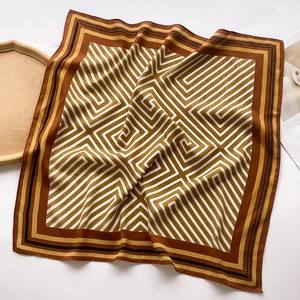 Detailed close-up of geometric pattern silk scarf with elegant brown chevron lines