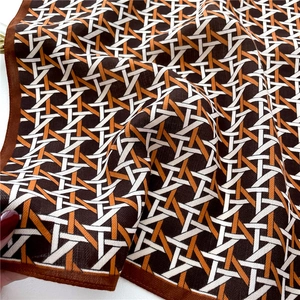 Detail of geometric woven pattern scarf in brown and orange silk-like fabric textures