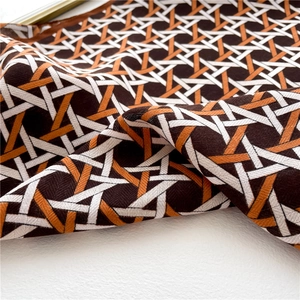 Detailed view of geometric star pattern scarf with luxurious twill texture and warm tones