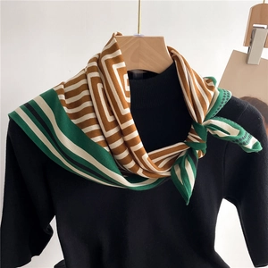 Elegant geometric patterned silk square scarf in brown and green on a black sweater