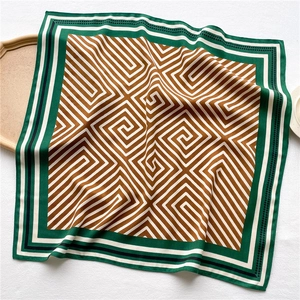Detailed view of square satin scarf showing geometric spiral patterns and silk-like texture