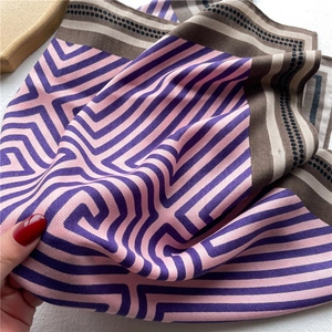 Close-up of geometric pattern silk scarf showing drape and glossy fabric texture