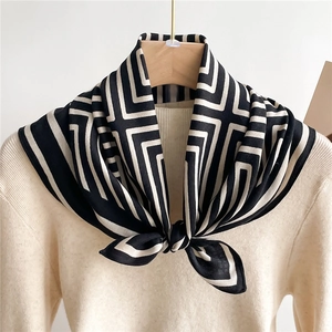 Elegant geometric pattern silk scarf with black and white stripes on a beige sweater