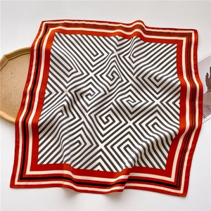 Detail of silk square scarf featuring black white geometric maze pattern and red border