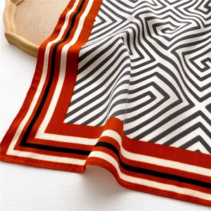 Detail of the geometric maze pattern silk scarf with bold orange and black striped borders