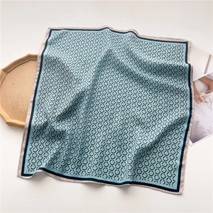 Détail d'un foulard en soie bleu clair avec motifs géométriques noirs et texture douce