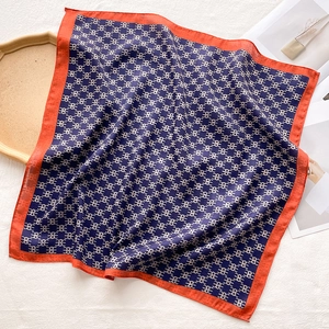 Detailed texture of navy blue and orange square silk scarf with geometric patterns