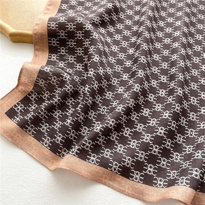 Detailed view of coffee silk scarf with double-E letter patterns and herringbone edges