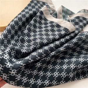 Macro detail of high-quality silk shawl showing grey geometric patterns and edge finish
