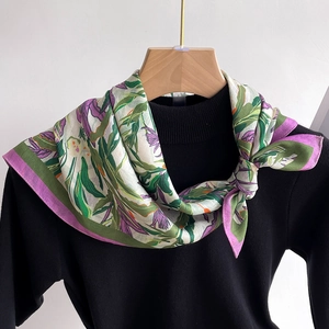 Detailed close-up of floral print silk scarf on a black sweater and wooden hanger