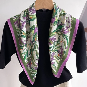 Detailed view of floral pattern scarf draped on a model neck with purple and green edge